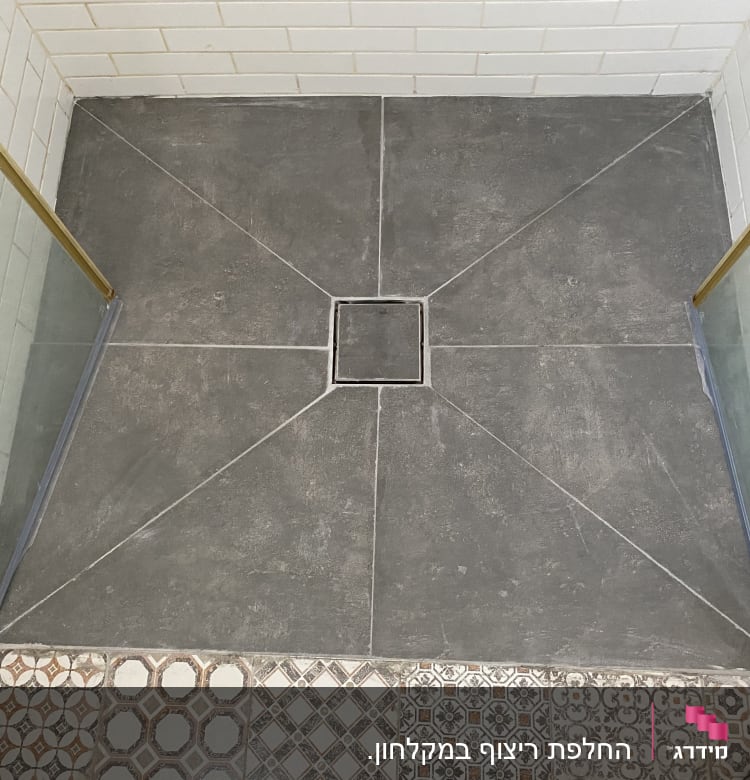 ריצוף חדש במקלחת עם אריחים אפורים וניקוז מרכזי